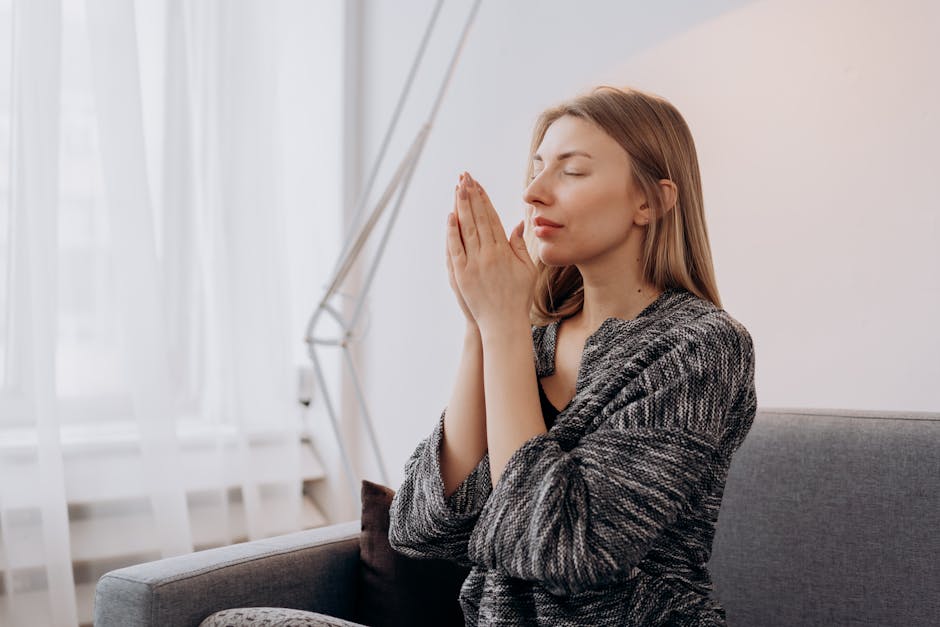 Woman meditating in a sunlit, peaceful living room setting.